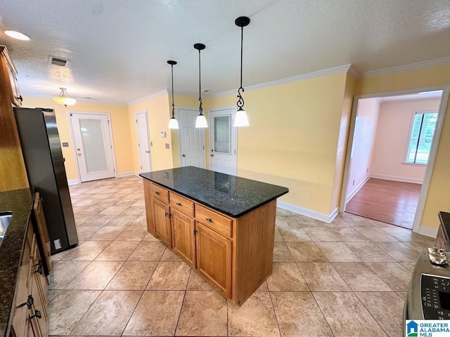 kitchen with freestanding refrigerator, a textured ceiling, ornamental molding, and baseboards