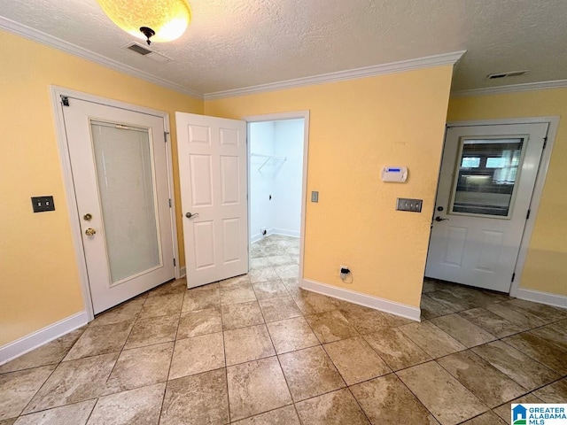 spare room with crown molding, a textured ceiling, visible vents, and baseboards