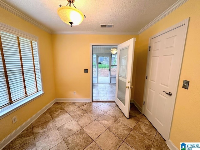 entryway featuring baseboards, ornamental molding, a textured ceiling, and visible vents