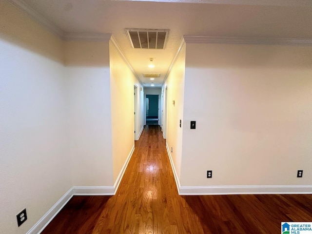 hall featuring crown molding, baseboards, visible vents, and wood finished floors