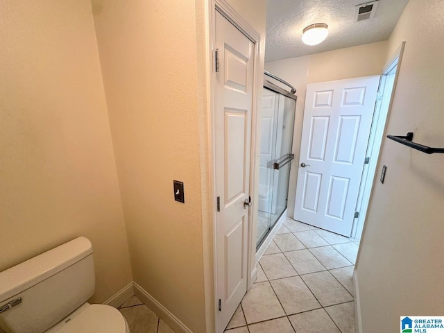 bathroom with visible vents, toilet, a textured ceiling, tile patterned floors, and a shower stall