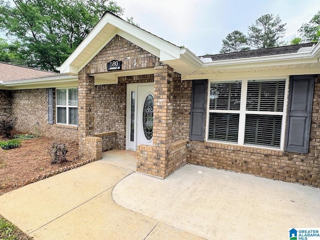 property entrance featuring a patio and brick siding