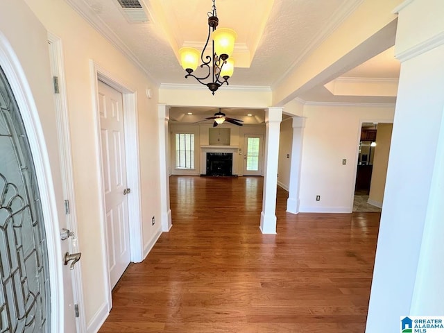 foyer entrance featuring a fireplace, light wood-style flooring, a ceiling fan, a tray ceiling, and visible vents