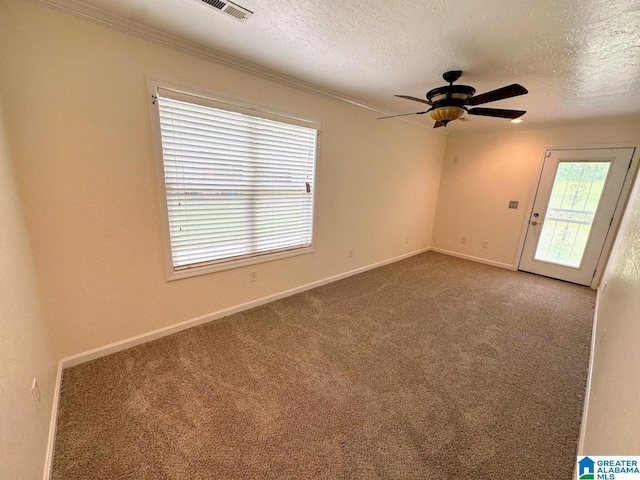 spare room with a ceiling fan, a textured ceiling, crown molding, baseboards, and carpet