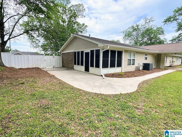 back of property featuring fence, a sunroom, a gate, cooling unit, and a lawn