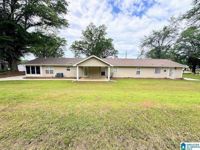rear view of property with a yard, a patio, and central AC
