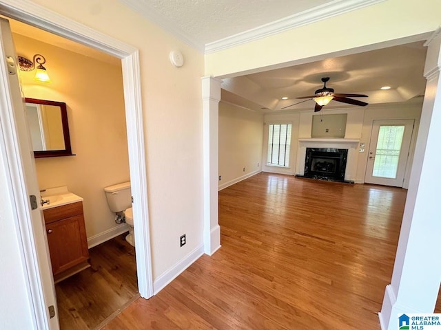 unfurnished living room with crown molding, ceiling fan, light wood-style floors, a premium fireplace, and baseboards