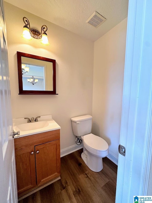 bathroom featuring visible vents, wood finished floors, baseboards, vanity, and toilet