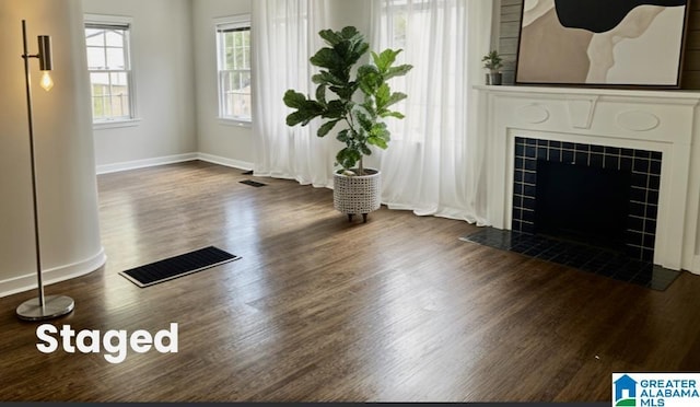 unfurnished living room with visible vents, baseboards, wood finished floors, and a tile fireplace