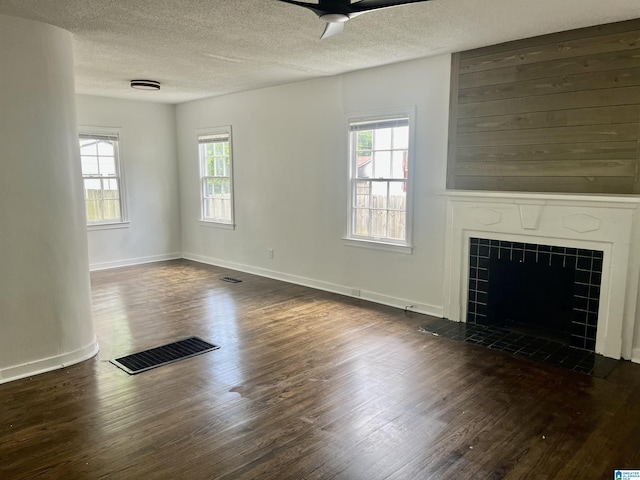 unfurnished living room featuring a healthy amount of sunlight, dark wood-style floors, and a textured ceiling