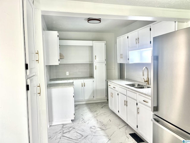 kitchen with open shelves, a sink, marble finish floor, freestanding refrigerator, and tasteful backsplash