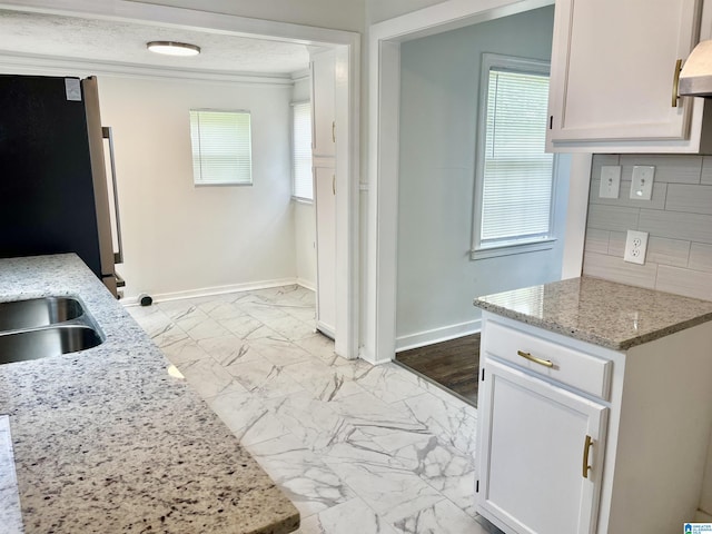 kitchen featuring crown molding, freestanding refrigerator, marble finish floor, baseboards, and a wealth of natural light
