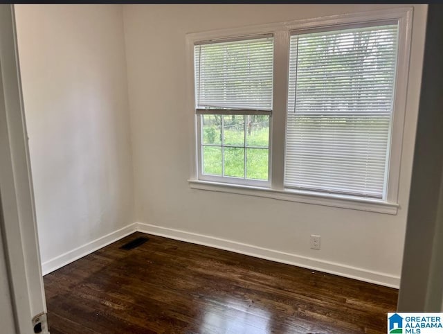 spare room featuring baseboards, dark wood finished floors, and visible vents