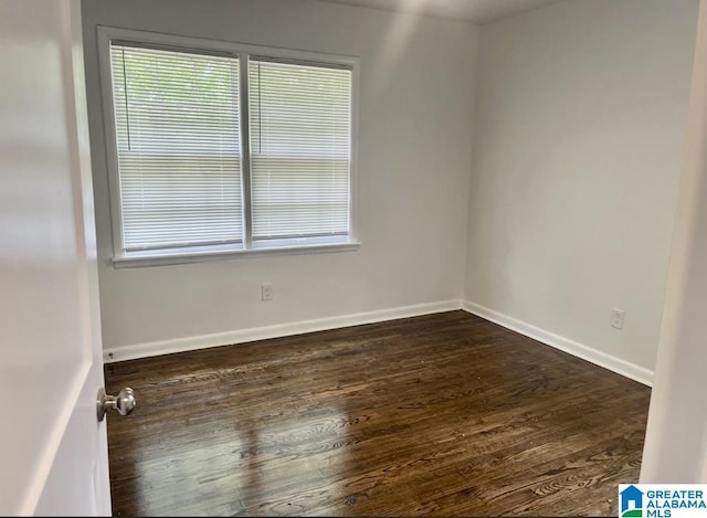 empty room featuring baseboards and dark wood-style floors