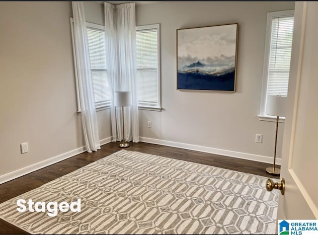 empty room with baseboards and dark wood-style flooring