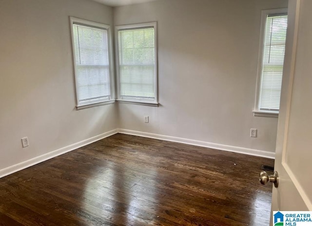 spare room with baseboards and wood finished floors