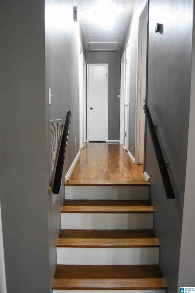 stairs featuring baseboards, visible vents, wood finished floors, and attic access