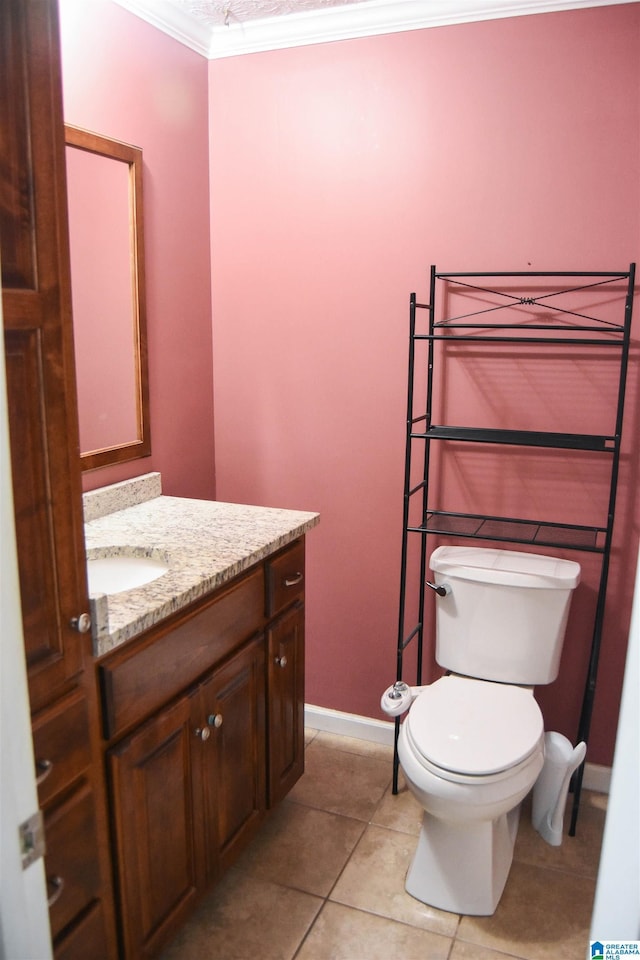 bathroom featuring tile patterned flooring, vanity, baseboards, toilet, and ornamental molding