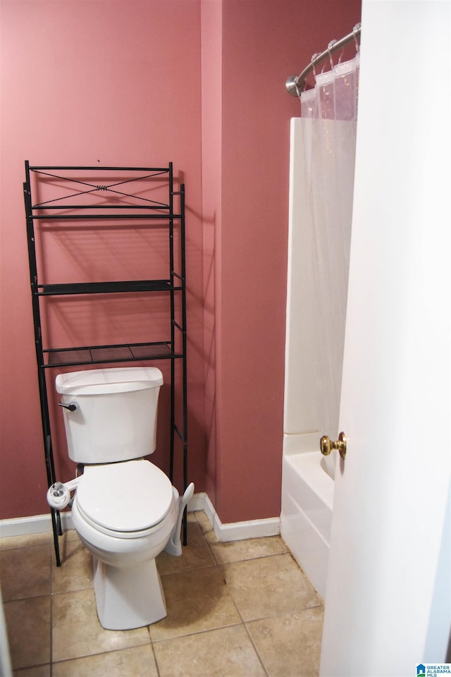bathroom with toilet, baseboards, and tile patterned flooring