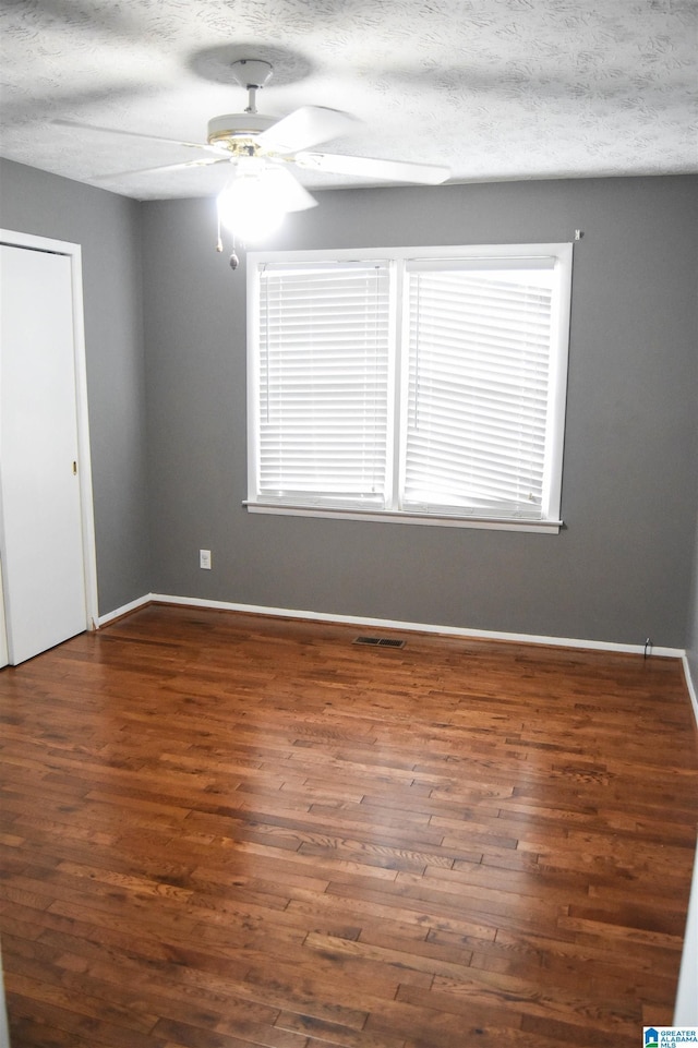 unfurnished bedroom featuring visible vents, baseboards, a textured ceiling, and wood finished floors
