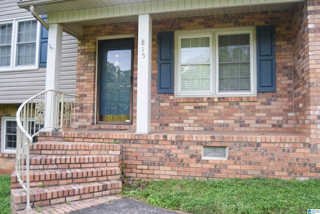view of exterior entry with covered porch and brick siding