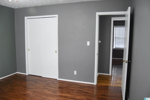 unfurnished bedroom with baseboards, wood finished floors, and a closet