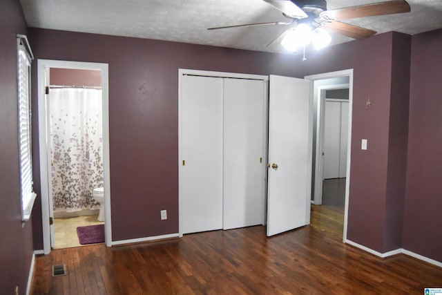 unfurnished bedroom featuring visible vents, wood finished floors, baseboards, a closet, and ensuite bath