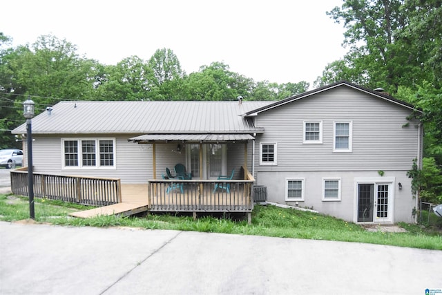 rear view of property with a deck, metal roof, and central AC unit