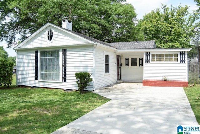 view of front of property with a shingled roof, a front lawn, and a chimney