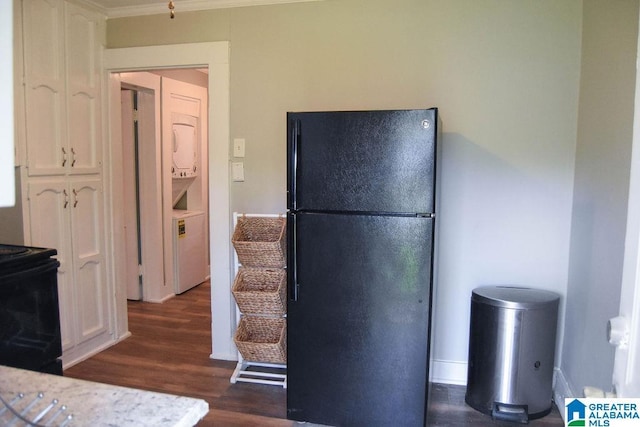 kitchen featuring crown molding, white cabinets, dark wood-style floors, black appliances, and stacked washer and clothes dryer