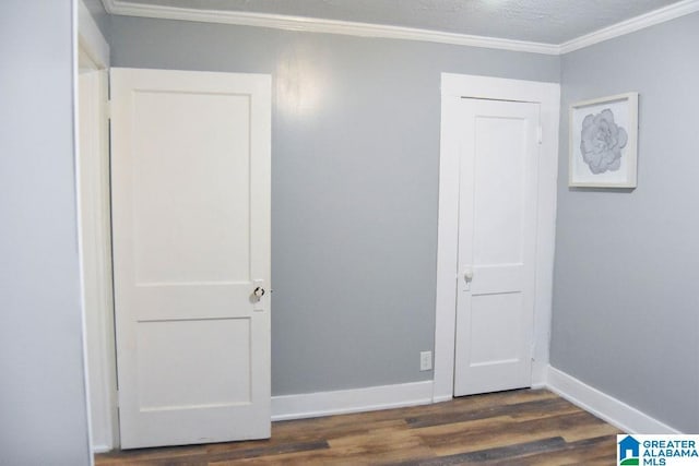 unfurnished bedroom featuring crown molding, baseboards, dark wood-style floors, and a textured ceiling