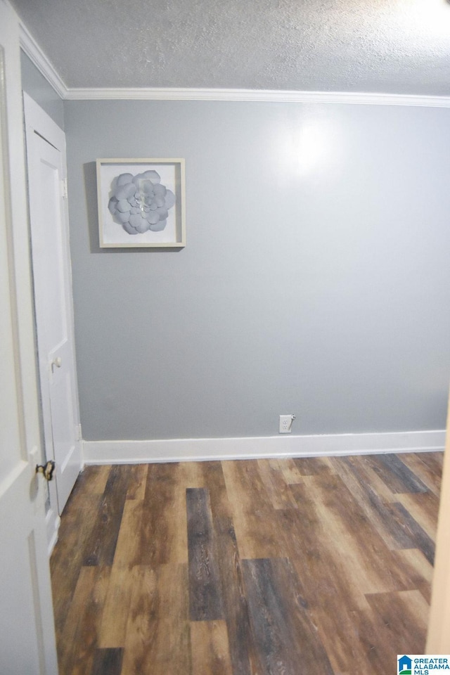 interior space with baseboards, ornamental molding, a textured ceiling, and wood finished floors