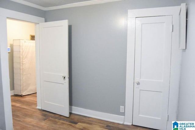 unfurnished bedroom featuring crown molding, baseboards, and wood finished floors