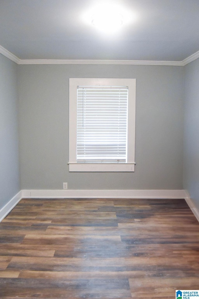 spare room with crown molding, baseboards, and wood finished floors