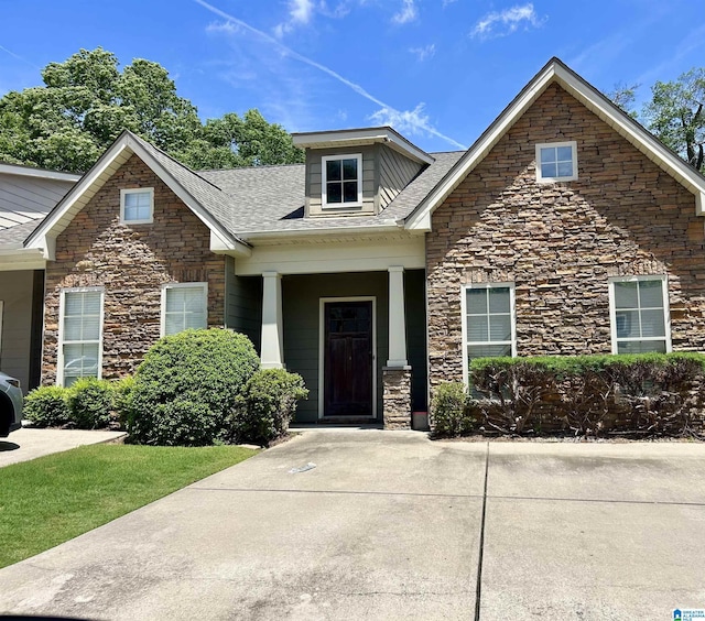 view of front of property with stone siding and a shingled roof