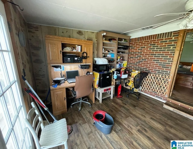 home office featuring a ceiling fan, wood finished floors, and brick wall