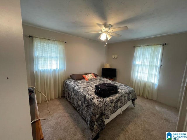 bedroom featuring ceiling fan, light carpet, and multiple windows