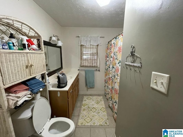 bathroom with a textured ceiling, tile patterned floors, baseboards, vanity, and toilet
