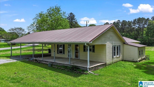 view of front facade featuring an attached carport, metal roof, covered porch, and a front lawn