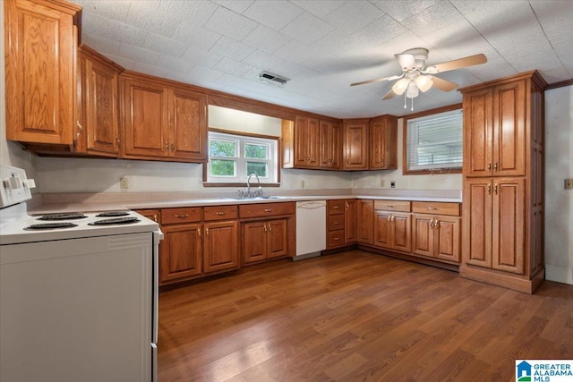 kitchen featuring a sink, brown cabinetry, white appliances, and visible vents
