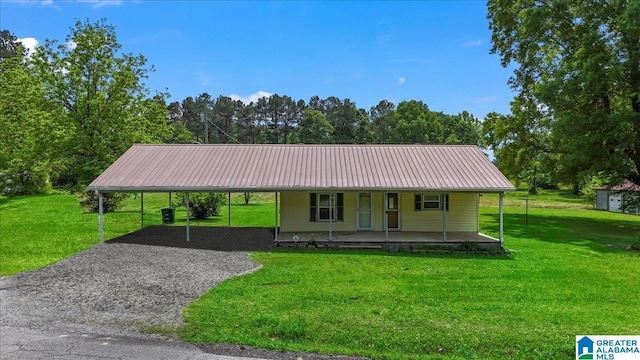 farmhouse featuring covered porch, gravel driveway, metal roof, and a front lawn