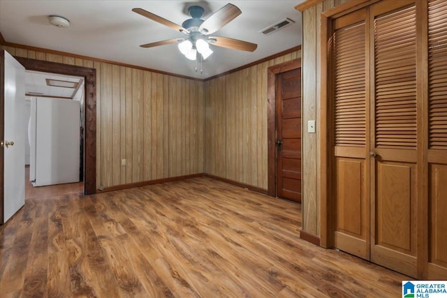 unfurnished bedroom featuring freestanding refrigerator, baseboards, visible vents, and wood finished floors