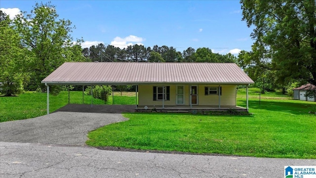 farmhouse-style home featuring covered porch, driveway, metal roof, a carport, and a front lawn