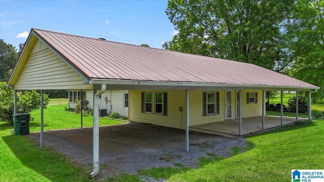 exterior space with metal roof, cooling unit, a yard, and a carport