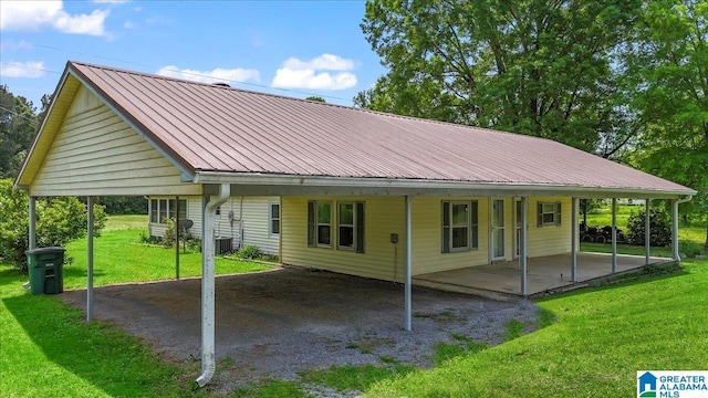 back of house featuring a carport, a yard, and metal roof