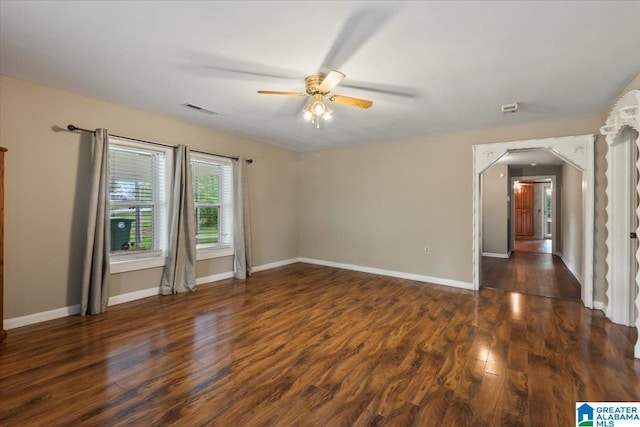 empty room with baseboards, ceiling fan, visible vents, and wood finished floors