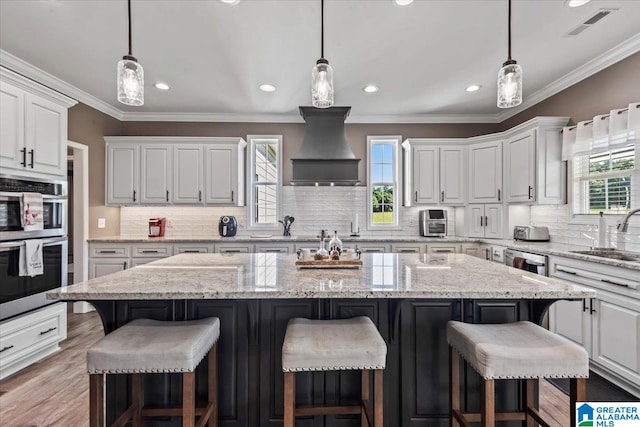 1520 Day Gap Rd, Cullman, AL 35057 - kitchen featuring decorative backsplash, a kitchen island, premium range hood, white cabinets, and a sink