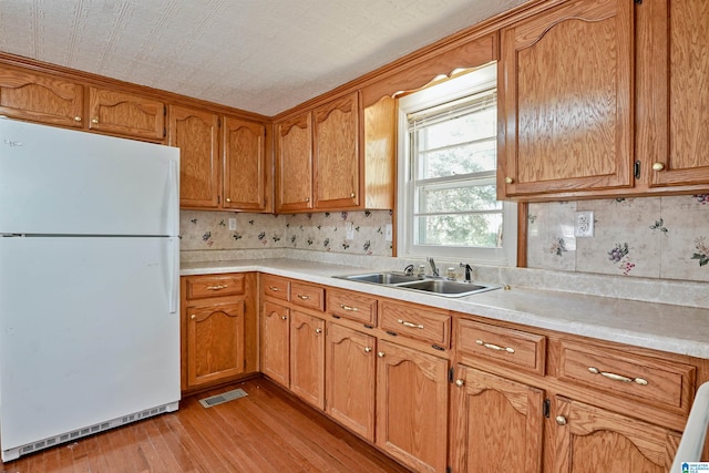 2928 University Way, Centreville, AL 35042 - kitchen featuring brown cabinets, a sink, light countertops, freestanding refrigerator, and light wood-style floors