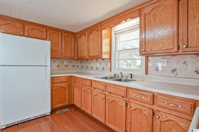 2928 University Way, Centreville, AL 35042 - kitchen with brown cabinets, a sink, light countertops, freestanding refrigerator, and light wood-style flooring