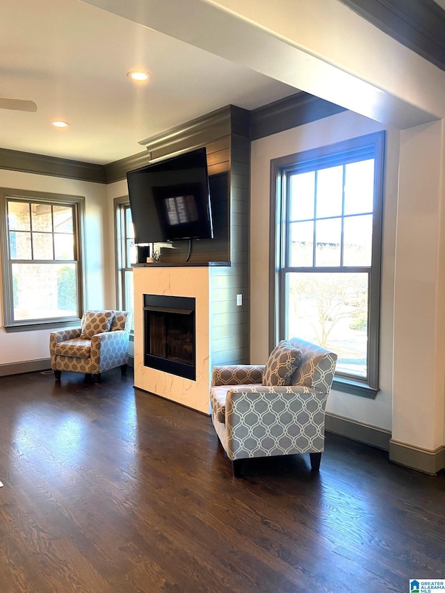 living area with a fireplace, dark wood finished floors, recessed lighting, baseboards, and ornamental molding